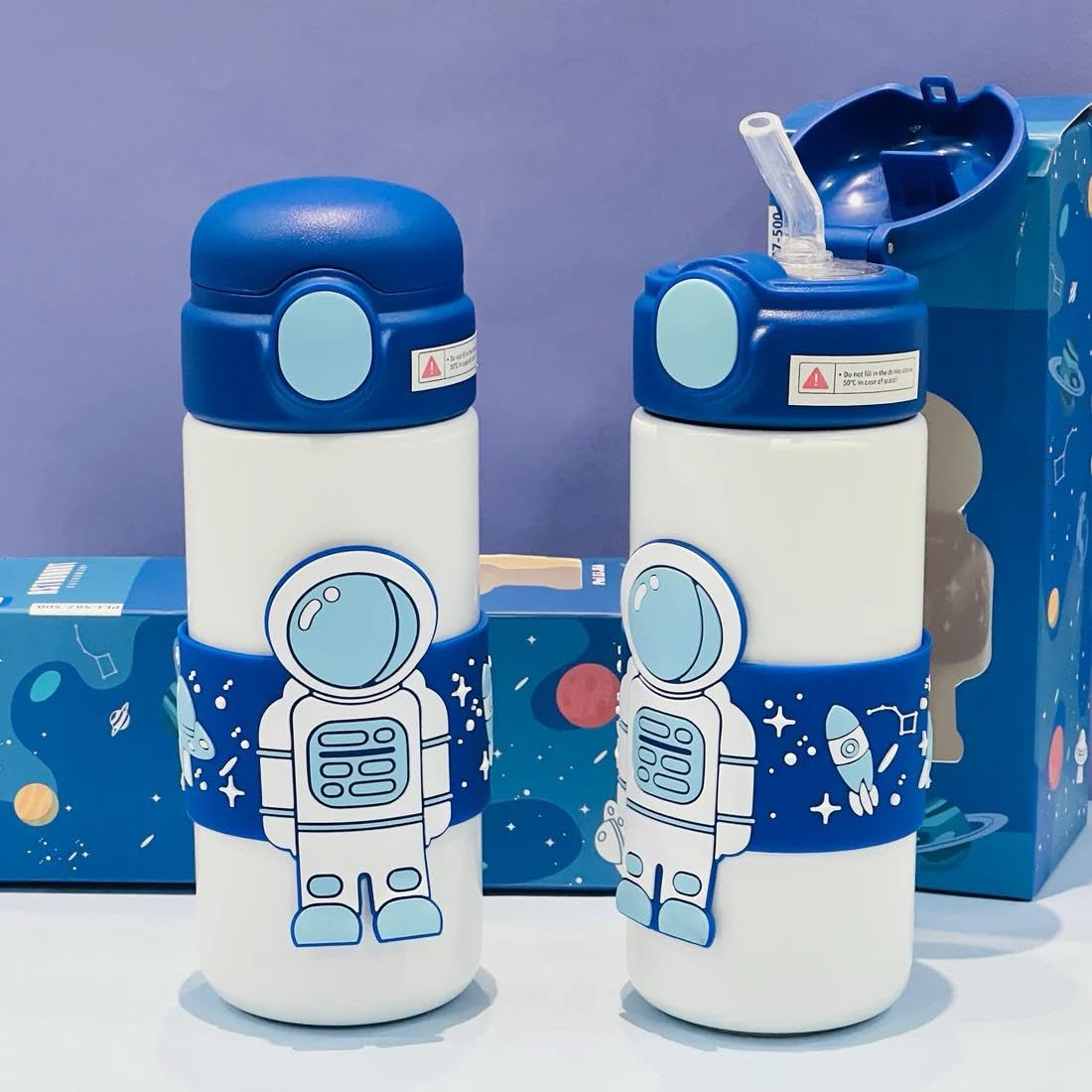 White stainless steel insulated water bottle for kids with a blue cap and a wrap-around blue band featuring an astronaut and space designs. 500 ML capacity. Ideal for hot or cold beverages for school and travel from uSmile.toys." www.usmile.toys